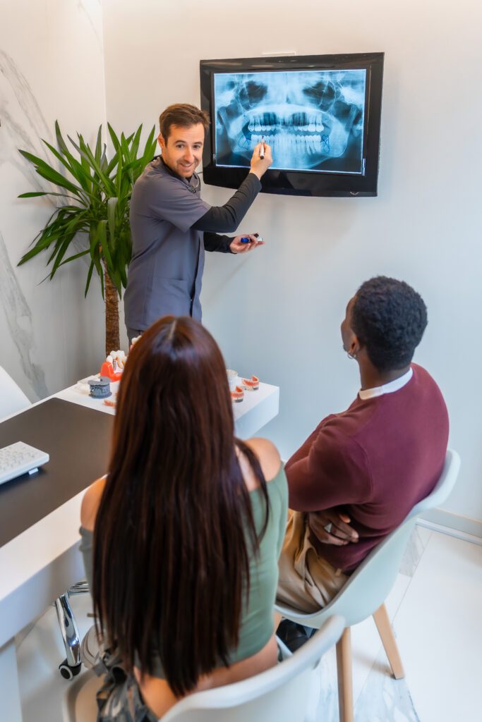 Dentist showing teeth x ray to patients in modern clinic